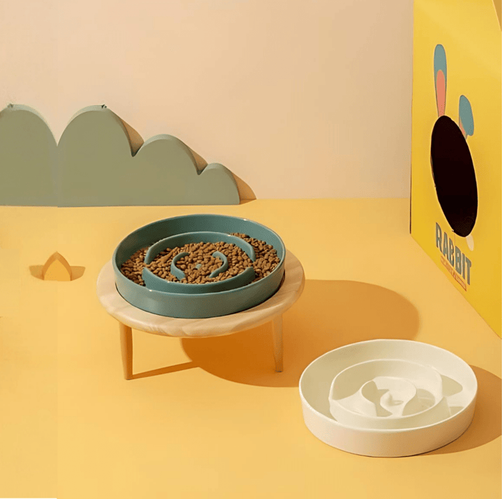 White ceramic dog slow feeder bowl with maze design on a wooden stand.
