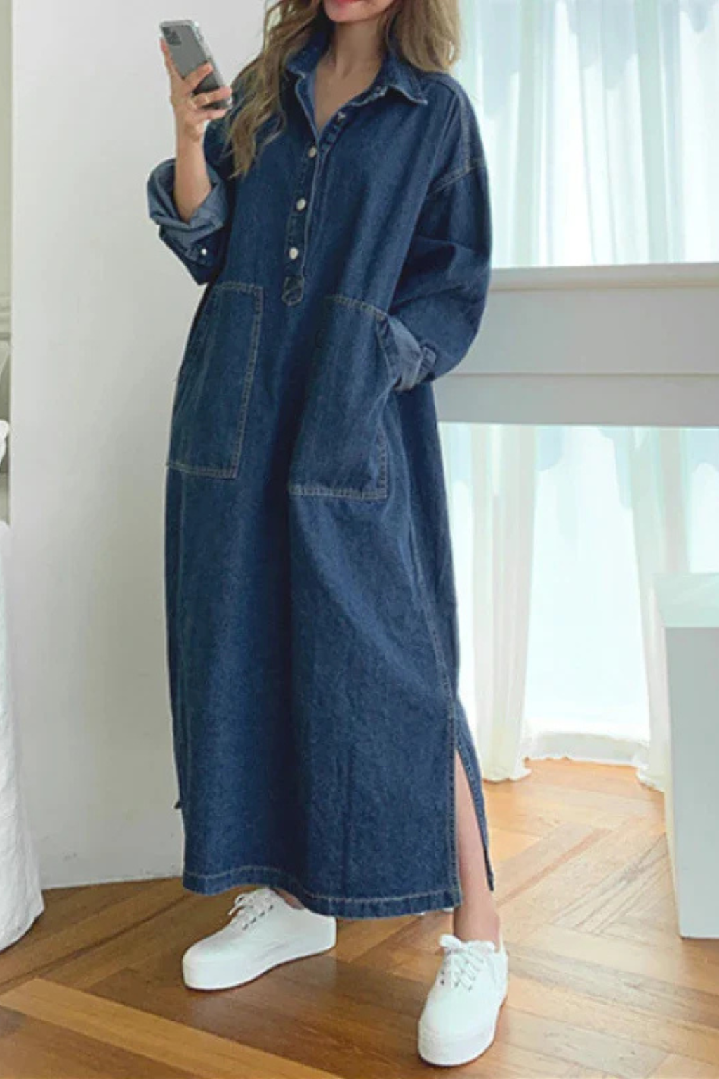 Modern women's long blue oversized shirt dress, with a relaxed silhouette, button details, and functional pockets.