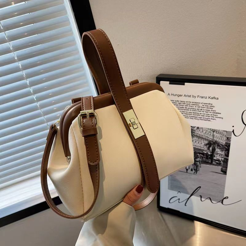 Structured brown women's handbag with adjustable crossbody strap and elegant top handle for versatility.