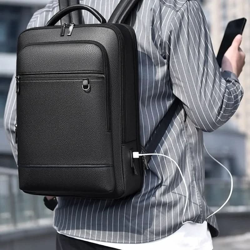 Durable PU leather work backpack with USB port, fits laptops for school or office, unisex style.