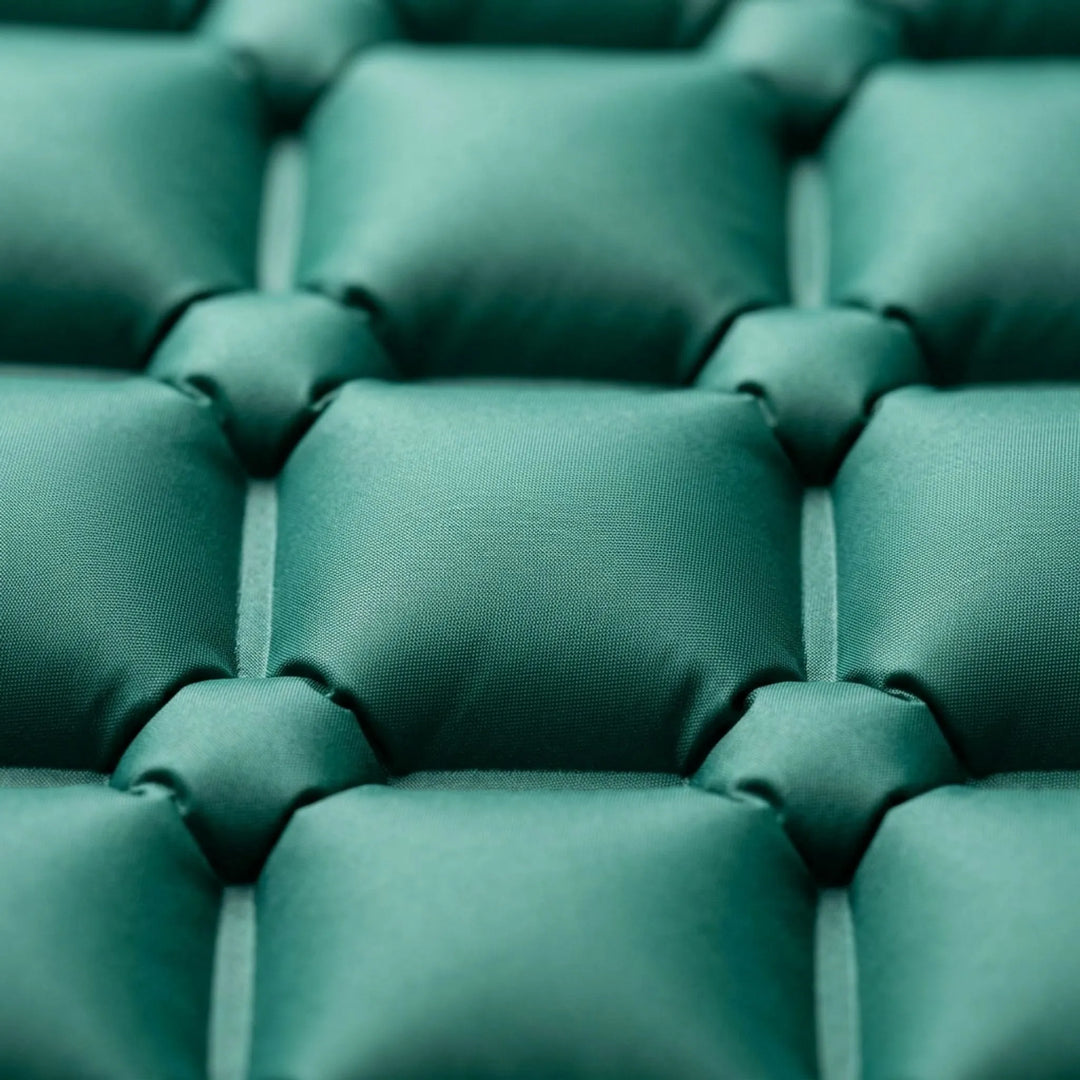 Hiker comfortably resting on an inflatable camping sleeping mat with built-in pillow in an outdoor setting.