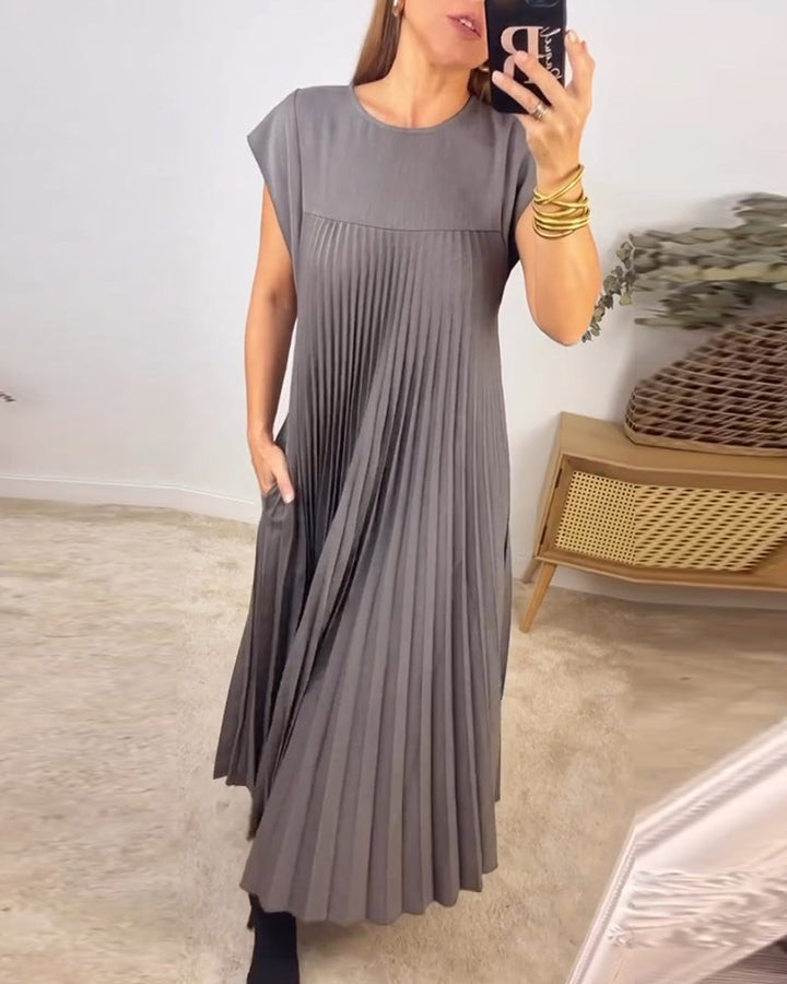 Woman wearing a chic pleated maxi dress, showing its flowing silhouette, elegant pleats & versatile design.