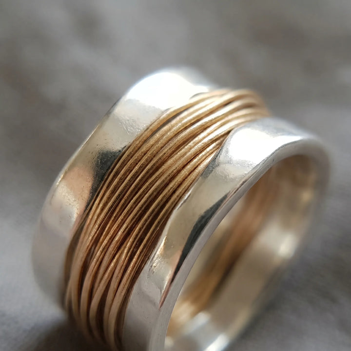 Delicate women's two-tone silver band ring adorned with a fine gold wire accent. An elegant fashion piece.