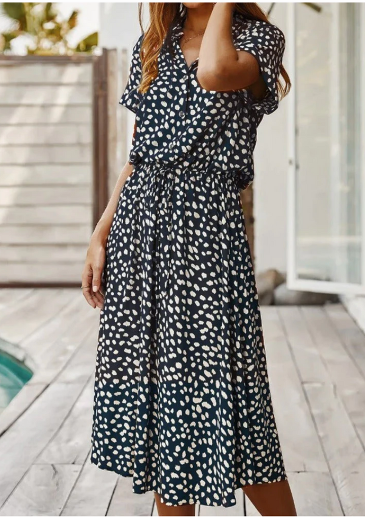 Close-up on flutter sleeve and V-neck detail of a women's spotted button-down midi dress.
