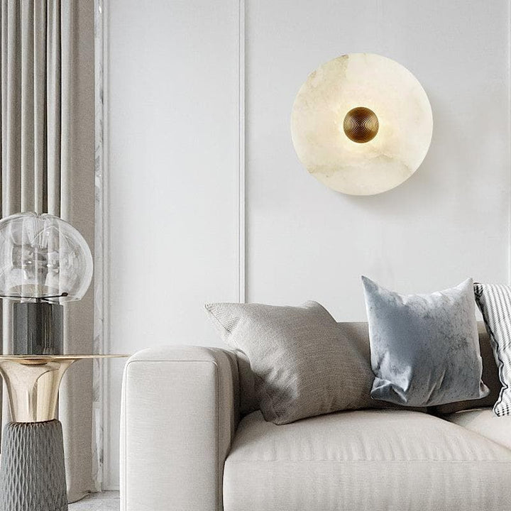 Round brass LED wall sconce with elegant alabaster shade, perfect modern luxury home decor lighting.