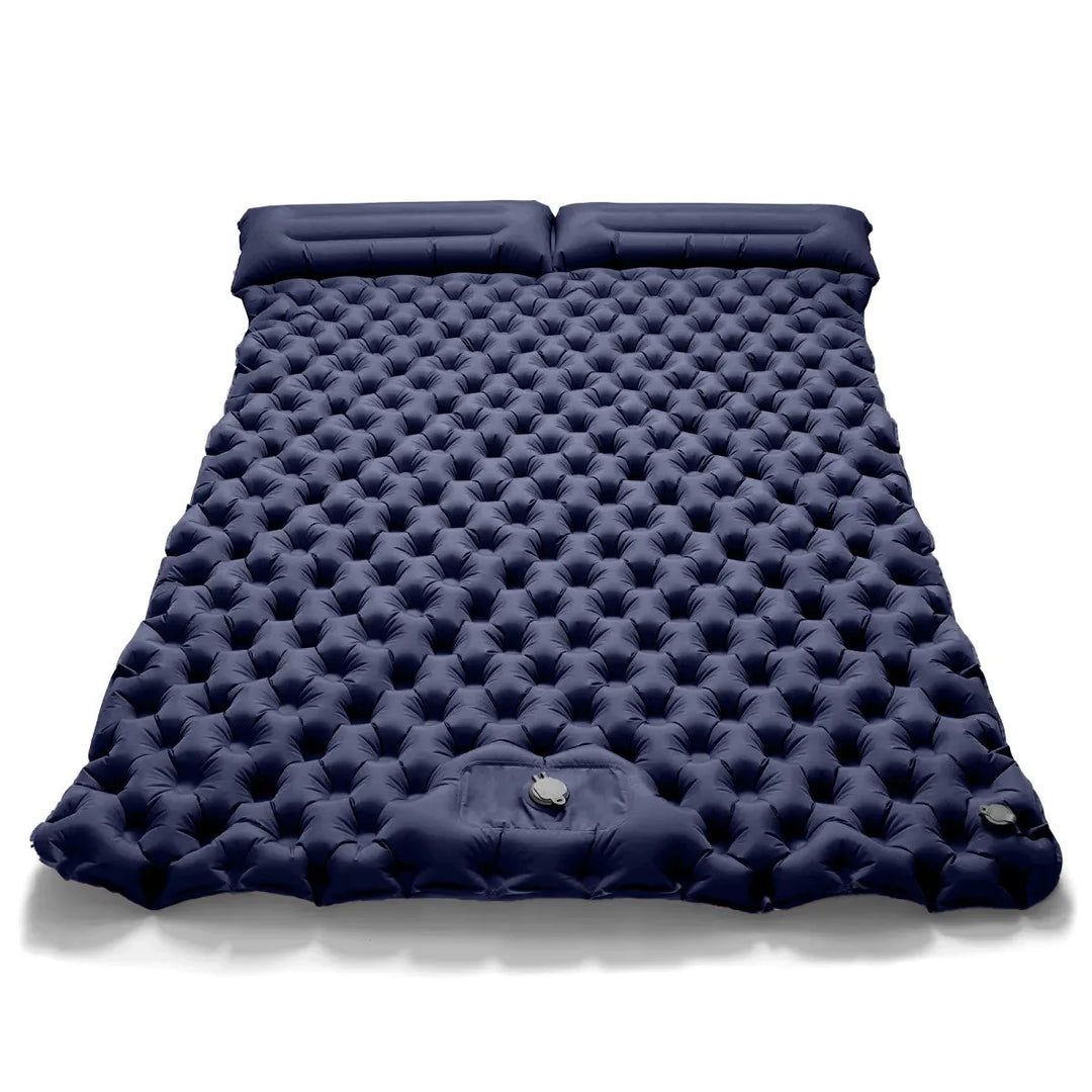 Person inflating dual camping air bed with integrated pump. Quick, easy setup for comfortable portable sleep.