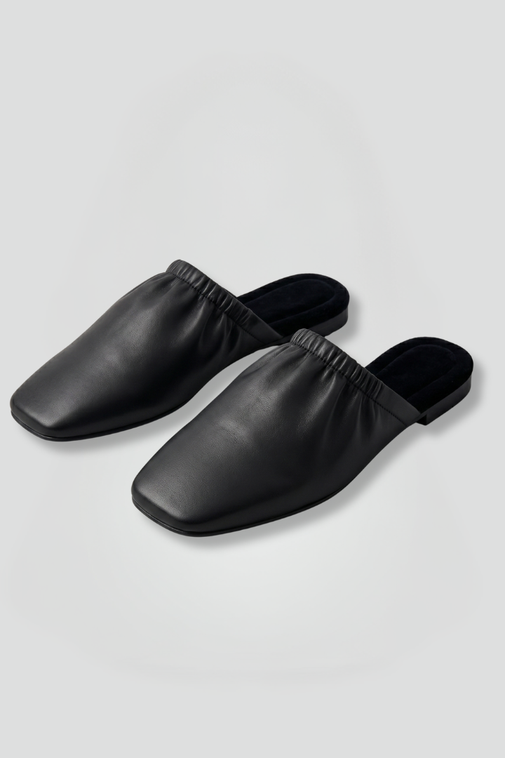 Black women's slip-on mule shoes with a chic cap toe design, perfect for casual or elegant everyday wear.