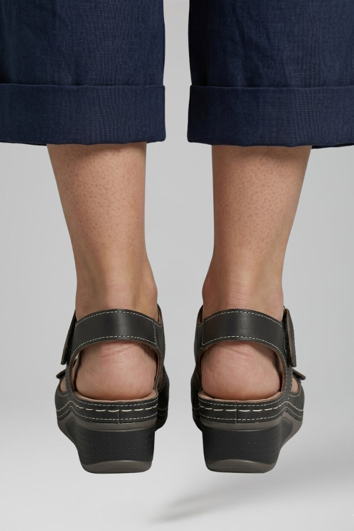Stylish women's black wedge sandals, offering comfort with a cushioned insole and practical adjustable strap.