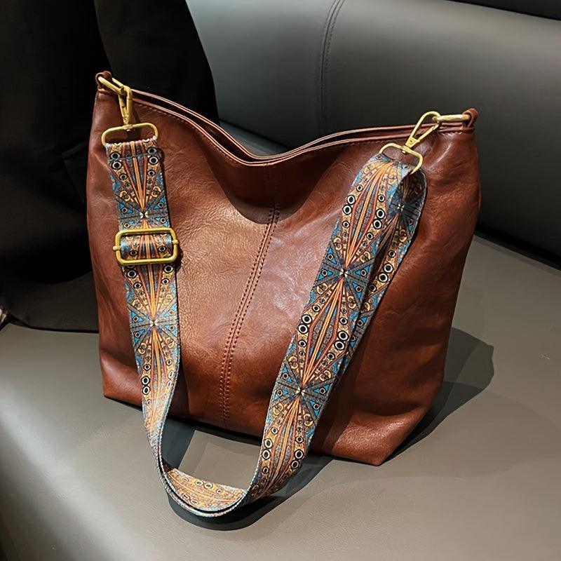 Spacious women's hobo shoulder bag in faux leather, with a distinctive patterned strap. Bohemian chic accessory.
