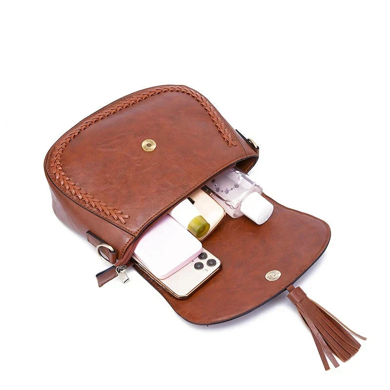 Front view of elegant brown women's saddle bag with chic tassel detail. Versatile crossbody shoulder fashion accessory.