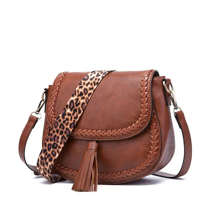 Side view of black women's saddle bag, showing elegant tassel & adjustable crossbody shoulder strap. Fashionable.