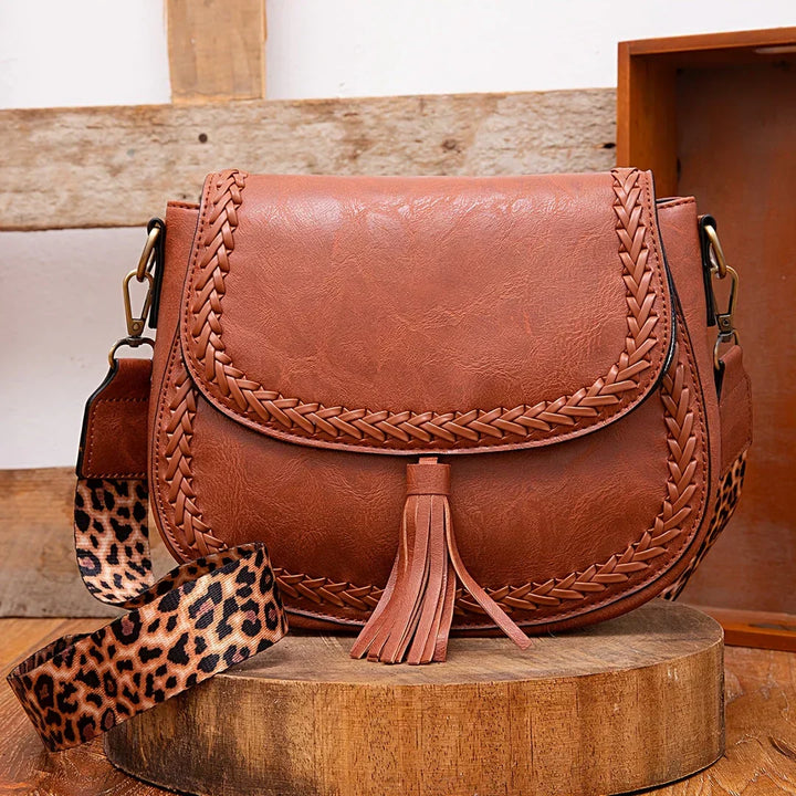 Elegant brown women's saddle bag with stylish tassel detail. Chic crossbody shoulder everyday fashion accessory.