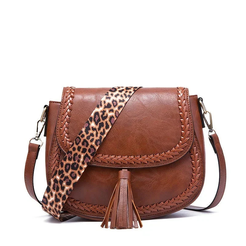 Black elegant women's saddle bag with a chic tassel. Stylish crossbody shoulder handbag for everyday fashion.