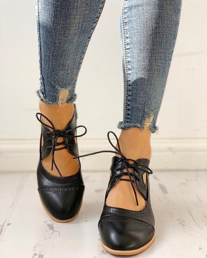 Close-up of a women's black heeled lace-up T-strap dress shoe, highlighting intricate details