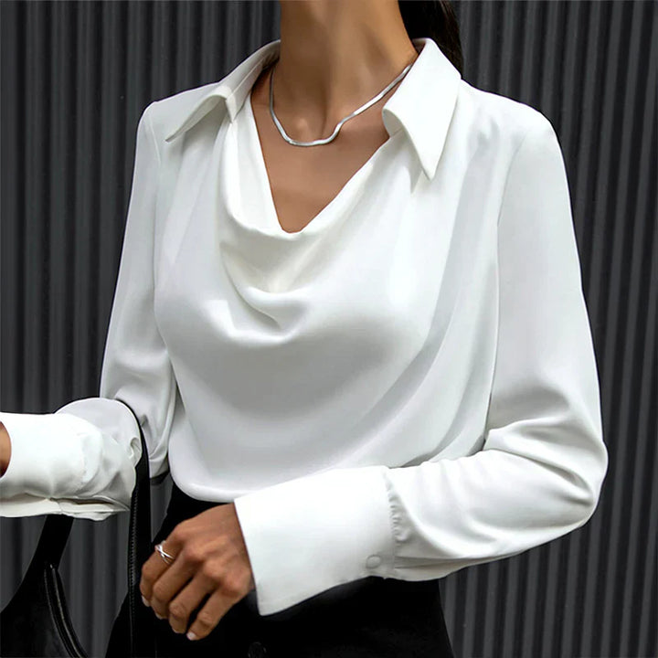 Stack of folded women's satin blouses in bronze, blue, and white, with drape necks and long sleeves.