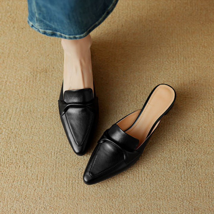Texture of the white leather on elegant women's mules with a classic bow