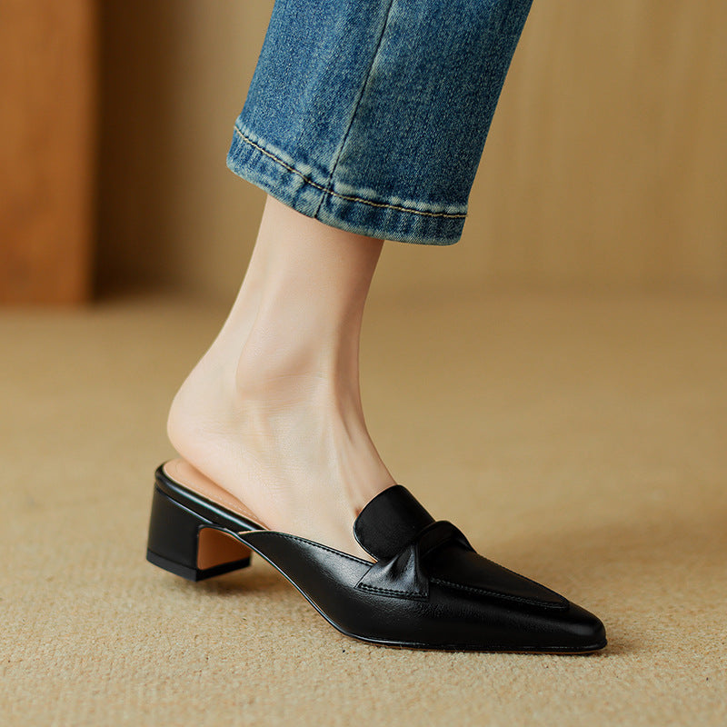 Detail shot of the black leather and bow on these chic women's slip-on mules