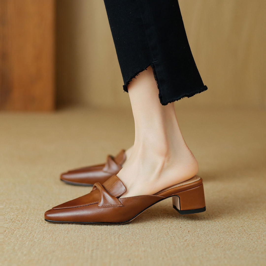 Sleek black leather mules for women, adorned with a sophisticated bow, ideal elegant footwear
