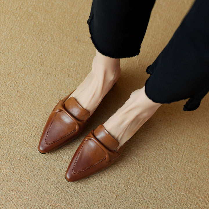 Women's brown leather mules with a decorative bow, offering slip-on ease and chic style