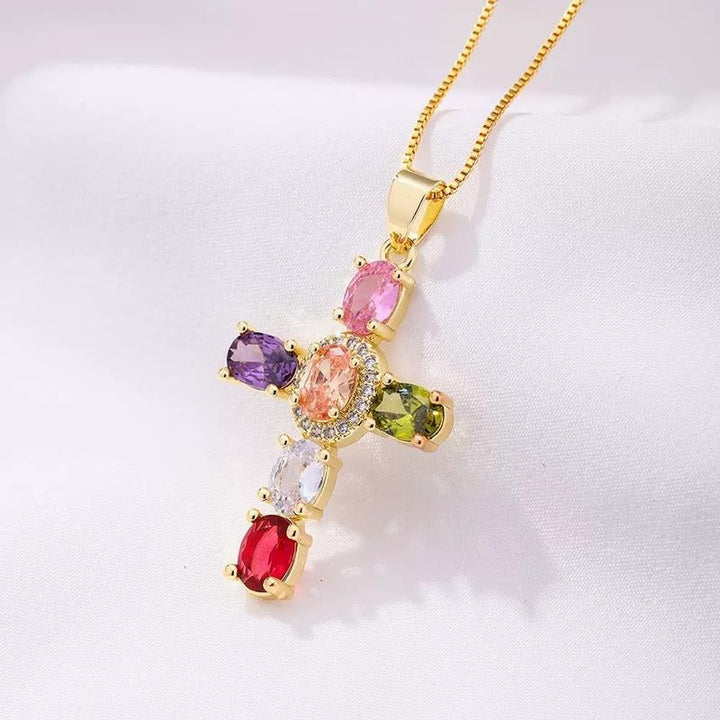 Close-up of a women's dainty gold plated cross necklace featuring intricate cubic zirconia gemstones