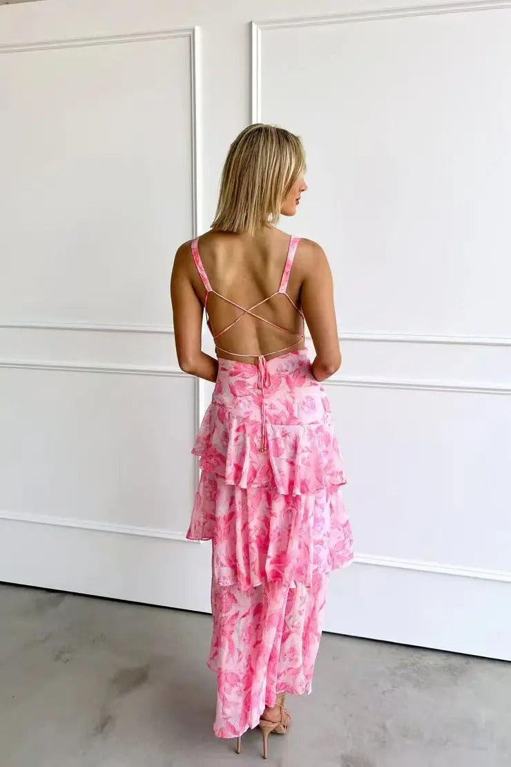 Woman wearing a fashionable printed V-neck maxi dress with ruffle tiers, styled for a wedding guest.