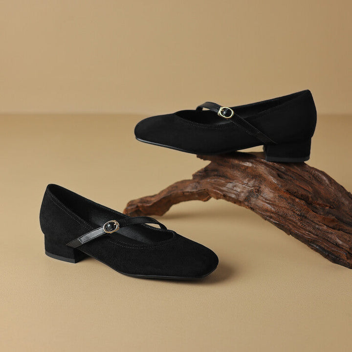 Lifestyle shot: woman wearing tan suede buckle strap block heel pumps, a comfortable choice.