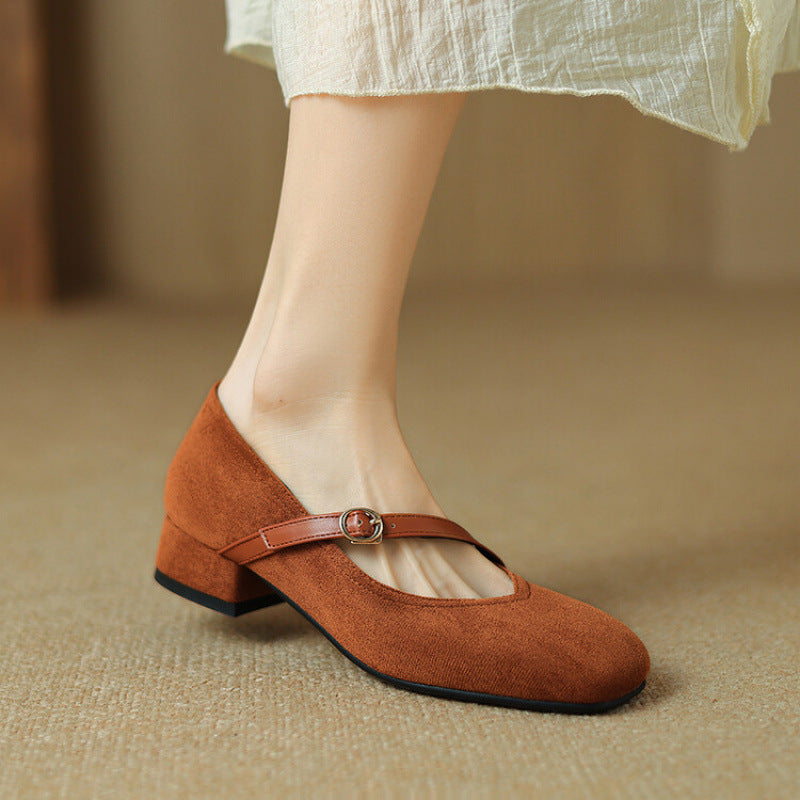 Close-up of the buckle strap on women's tan suede block heel pumps, highlighting detail.