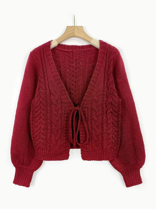Detailed shot of the tie-front closure on a women's elegant cable knit cardigan, acrylic blend.