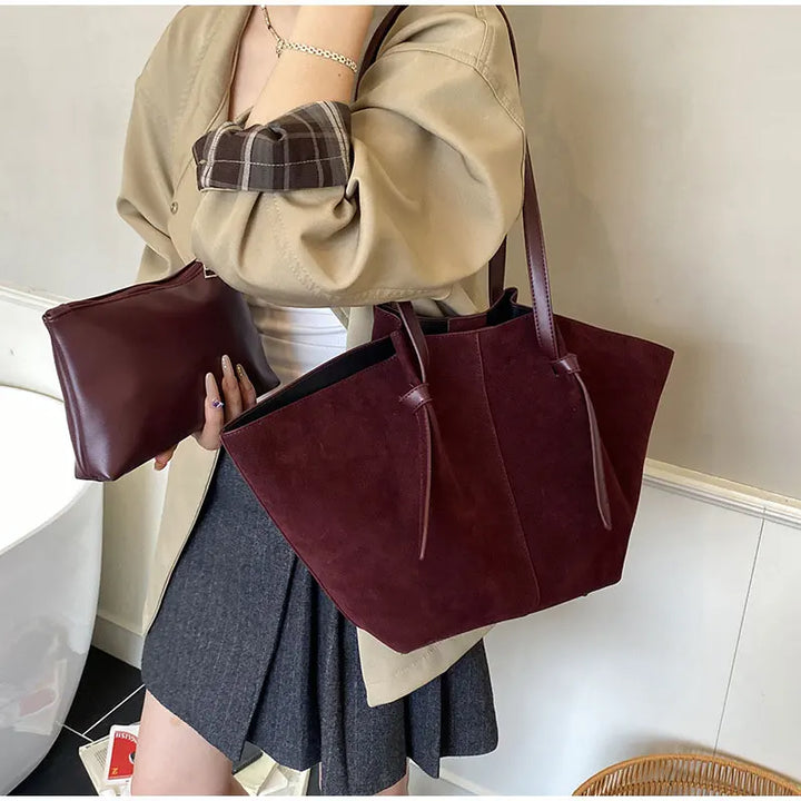Detail of the handle and stitching on an elegant women's faux suede tote handbag, a durable shoulder bag.