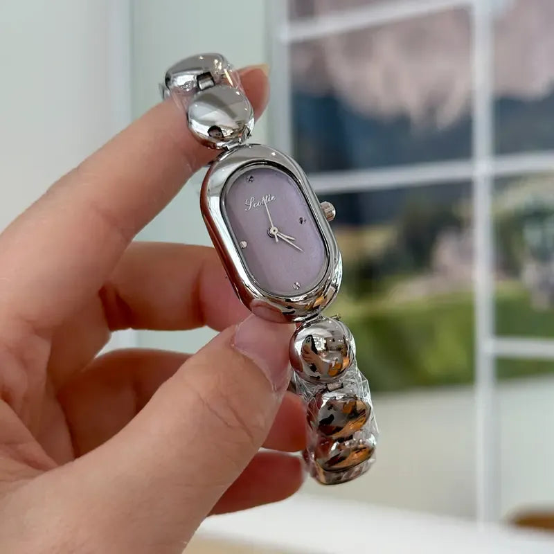 Women's oval minimalist stainless steel watch with a clean dial, indicating quartz movement.