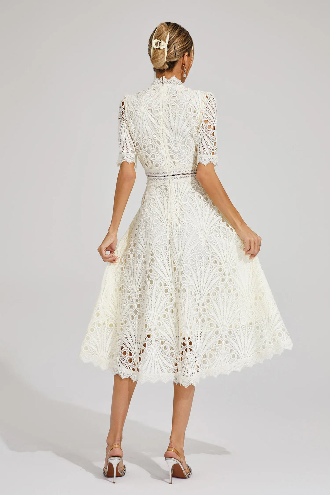 Model gracefully posing in a chic white lace midi dress, exuding elegance and style