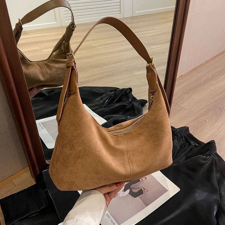 Close-up of a women's tan suede crescent bag, highlighting the soft texture and shoulder design.