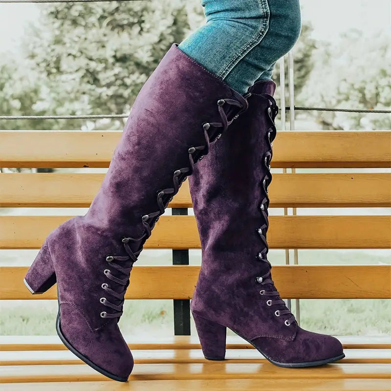 Close-up of a women's black tall lace-up boot, highlighting the block heel and sophisticated design