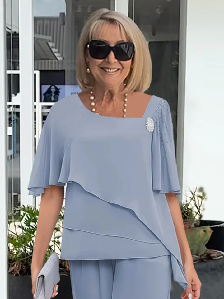 Women's elegant ensemble: a statement tiered cape top paired with comfortable wide-leg formal trousers.