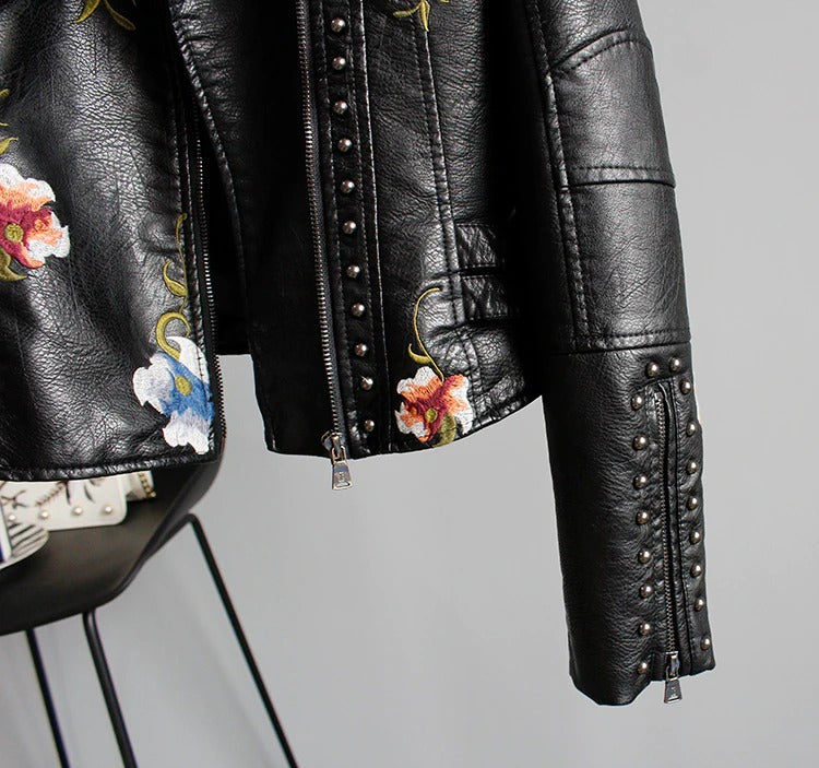 Detailed sleeve of a women's embroidered faux leather biker jacket with floral pattern.