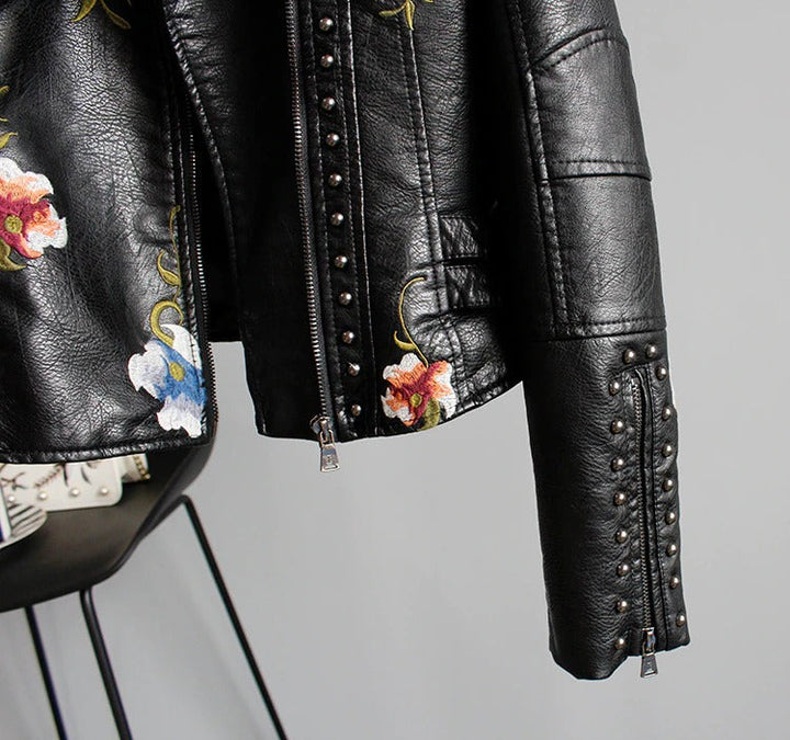 Detailed sleeve of a women's embroidered faux leather biker jacket with floral pattern.