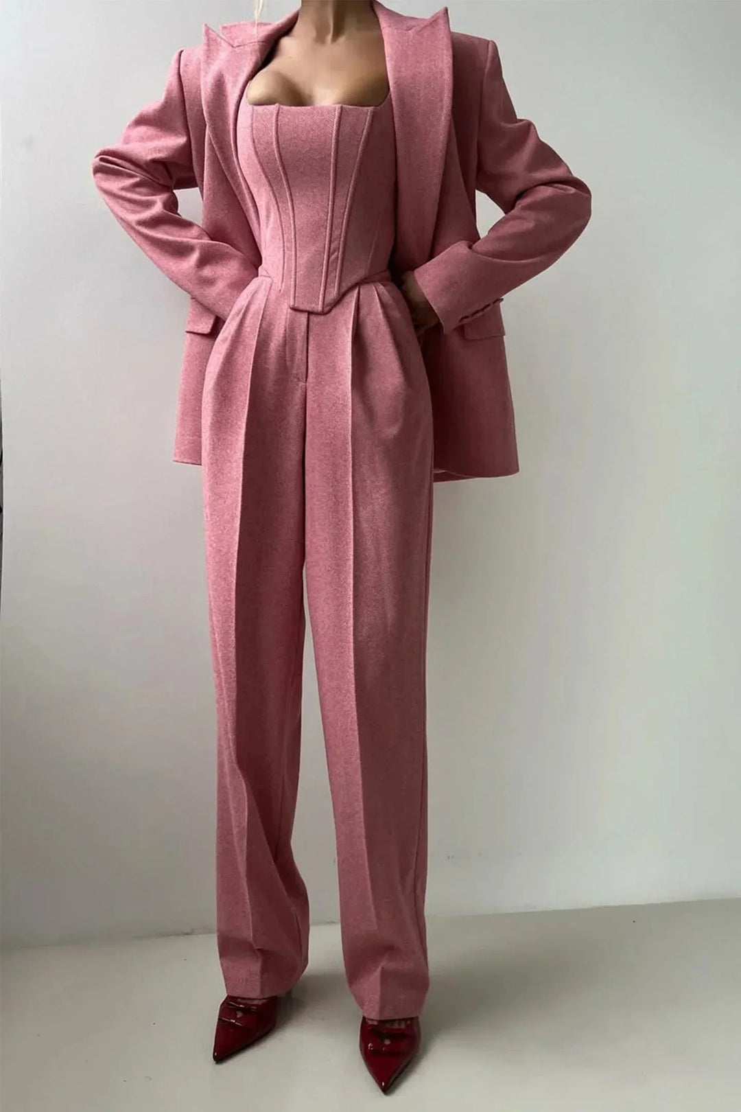 Full length shot of a woman wearing a chic 3-piece set: corset, wide leg pants & oversized blazer. Power dressing.
