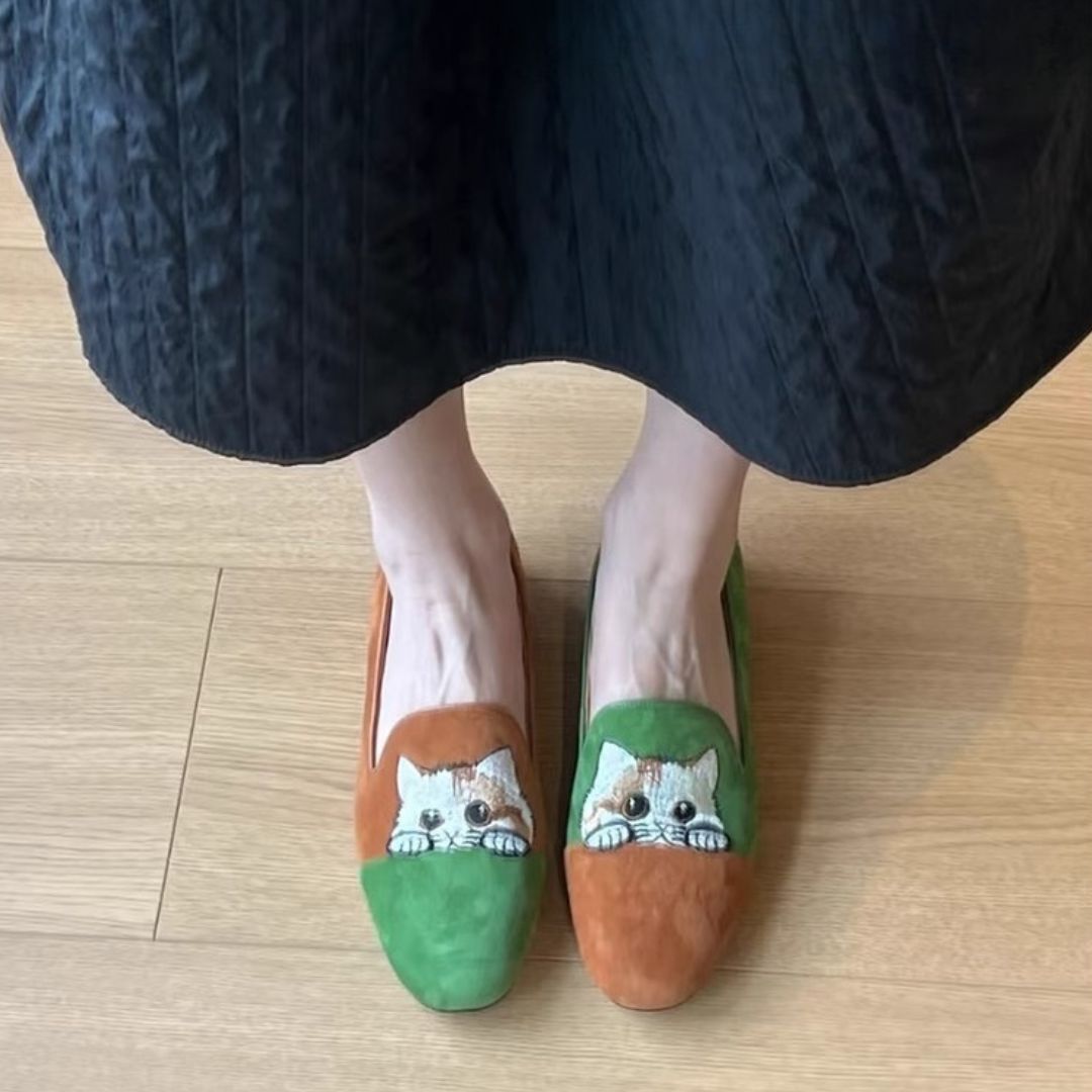Close-up of a women's green suede loafer, showcasing detailed embroidered cat motif and comfortable sole