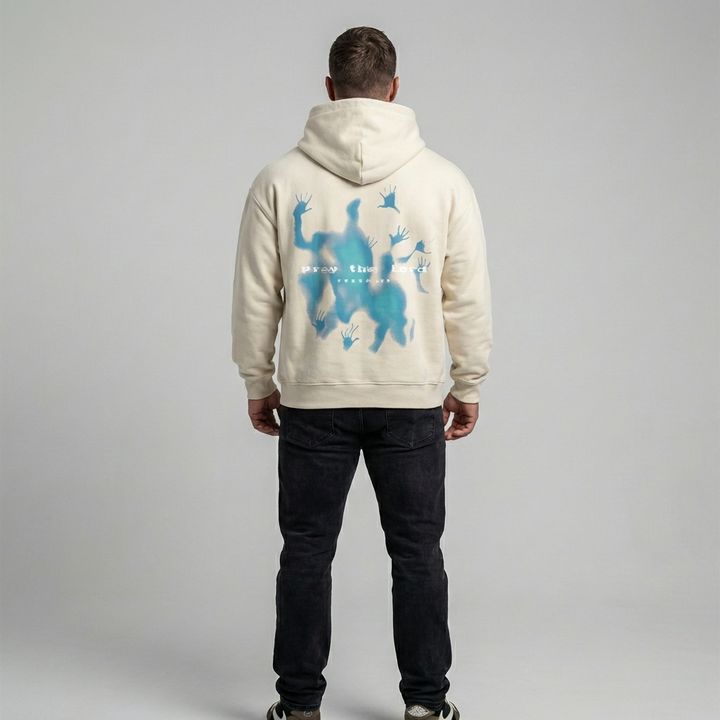 Model wearing a relaxed fit beige graphic oversized hoodie. Unisex streetwear fashion pullover for a casual, comfortable look.