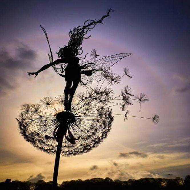 Enchanting metal fairy blowing dandelion seeds, a charming garden stake for mystical outdoor decor.