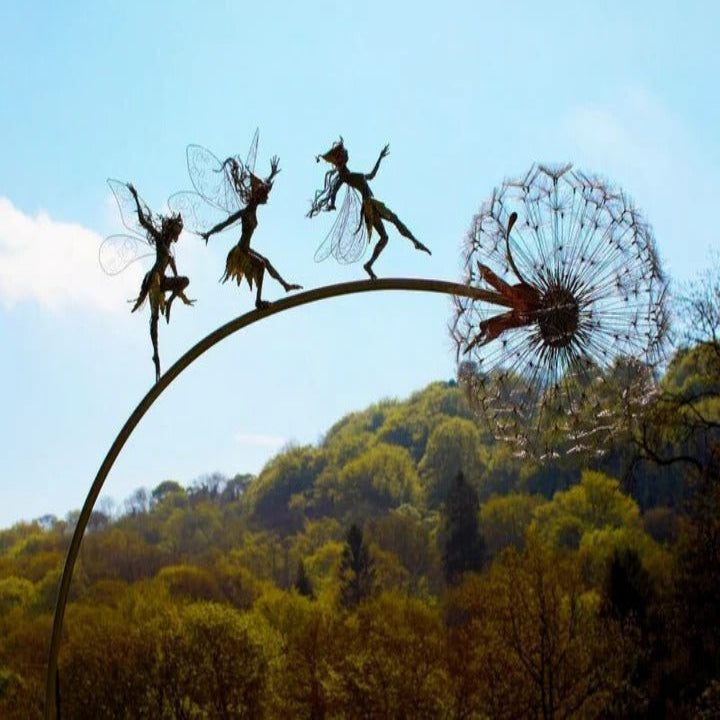 Detailed metal fairy figure perched on a dandelion stake, adding whimsical charm to garden landscape.