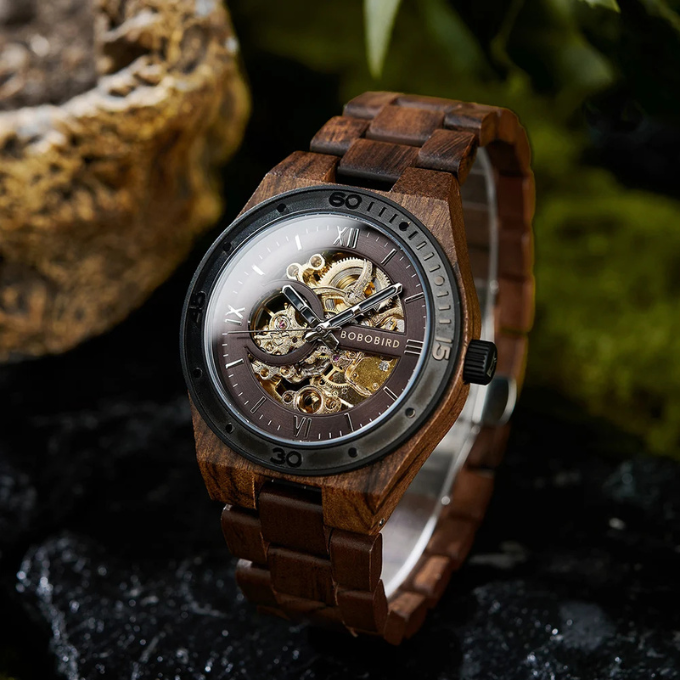 Close-up of men's mechanical skeleton watch, showing intricate gold movement, dark wood case.