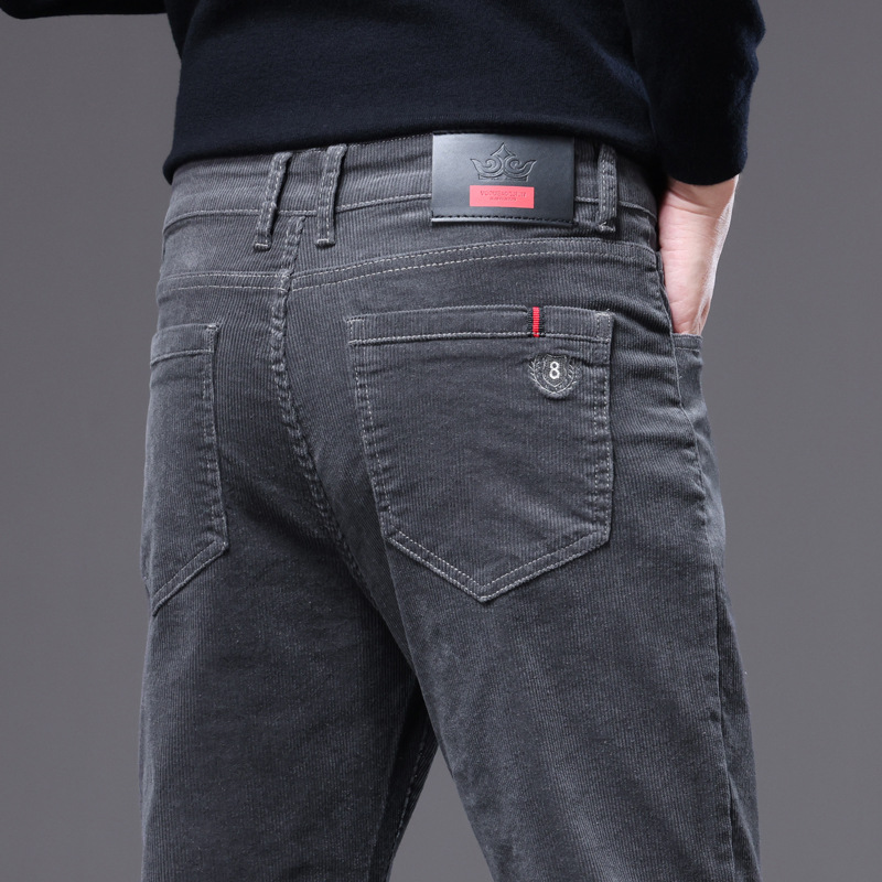 Close-up of the textured corduroy fabric on a pair of men's elegant black tailored trousers.