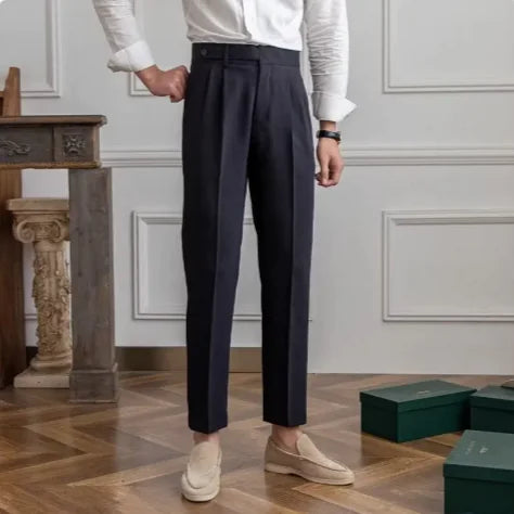 Detail of waistband and button closure on men's beige cropped suit trousers, emphasizing quality tailoring.