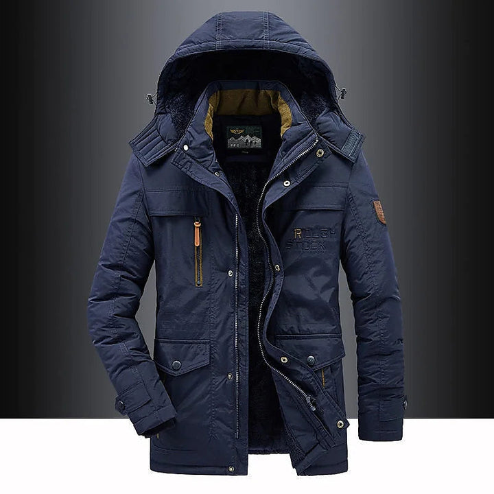 Full shot of man wearing a thigh-length hooded parka, suitable for severe winter conditions