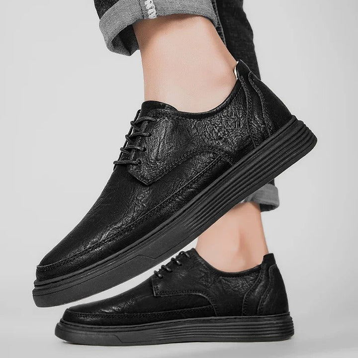 Men's black leather dress sneaker hybrid styled with chinos, demonstrating its smart casual appeal.