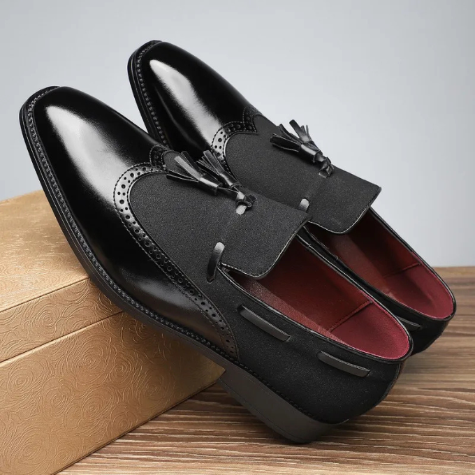 Close-up of men's dress shoes: leather tassel loafers with intricate brogue detailing on toe