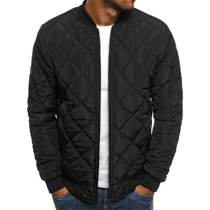 Man wearing a stylish quilted streetwear jacket in a city setting, showcasing modern men's apparel