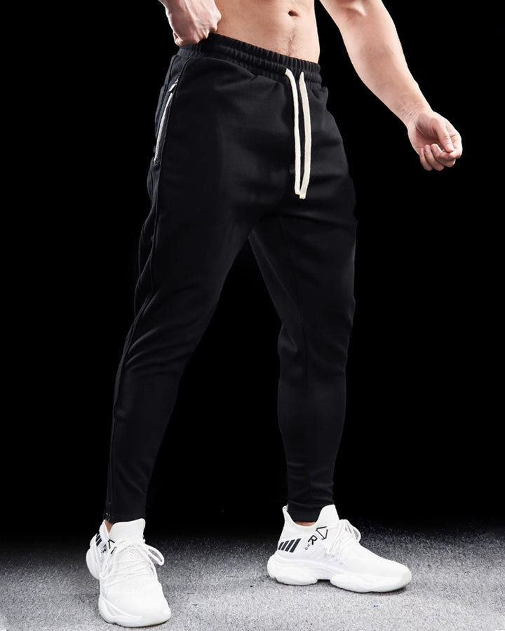 Detail of the comfortable elastic waistband and drawstring on men's tapered track joggers with zippered hems.