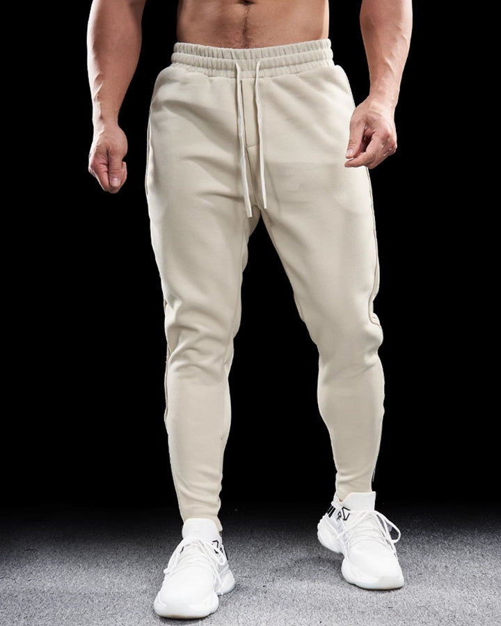 Front view of men's gray tapered track pants, zippered cuffs, suitable for activewear and comfortable style.